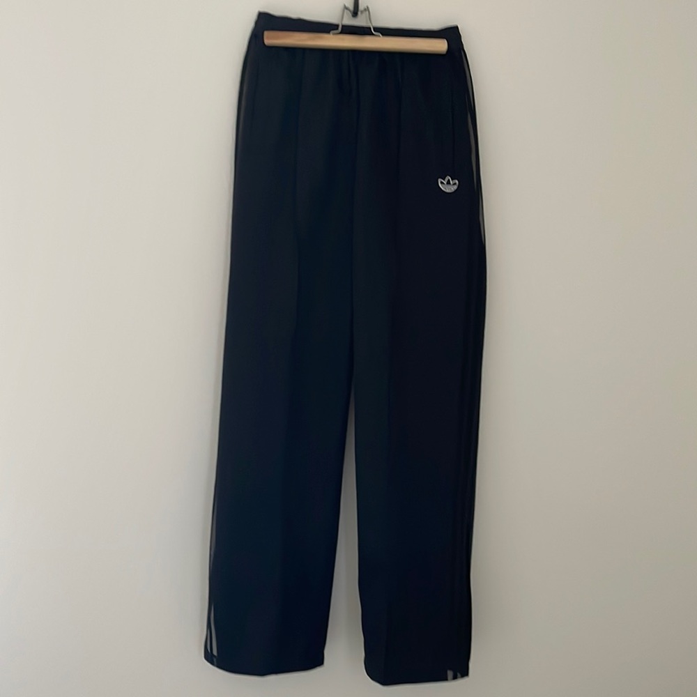 Adidas black track pants with transparent side detail.